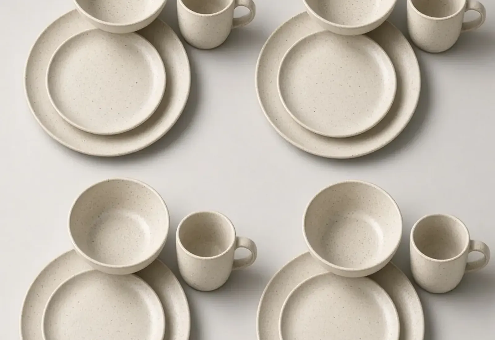 Speckled ceramic plates, bowls, and mugs arranged on a table